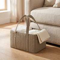 Khaki Bumpwell diaper caddy organizer on a living room floor beside a sofa