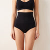 Woman wearing the black Bumpwell seamless high-waist postpartum brief