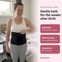 Woman wearing the black Bumpwell postpartum belly wrap over a white tank top: adjustable, wide band, stretch knit