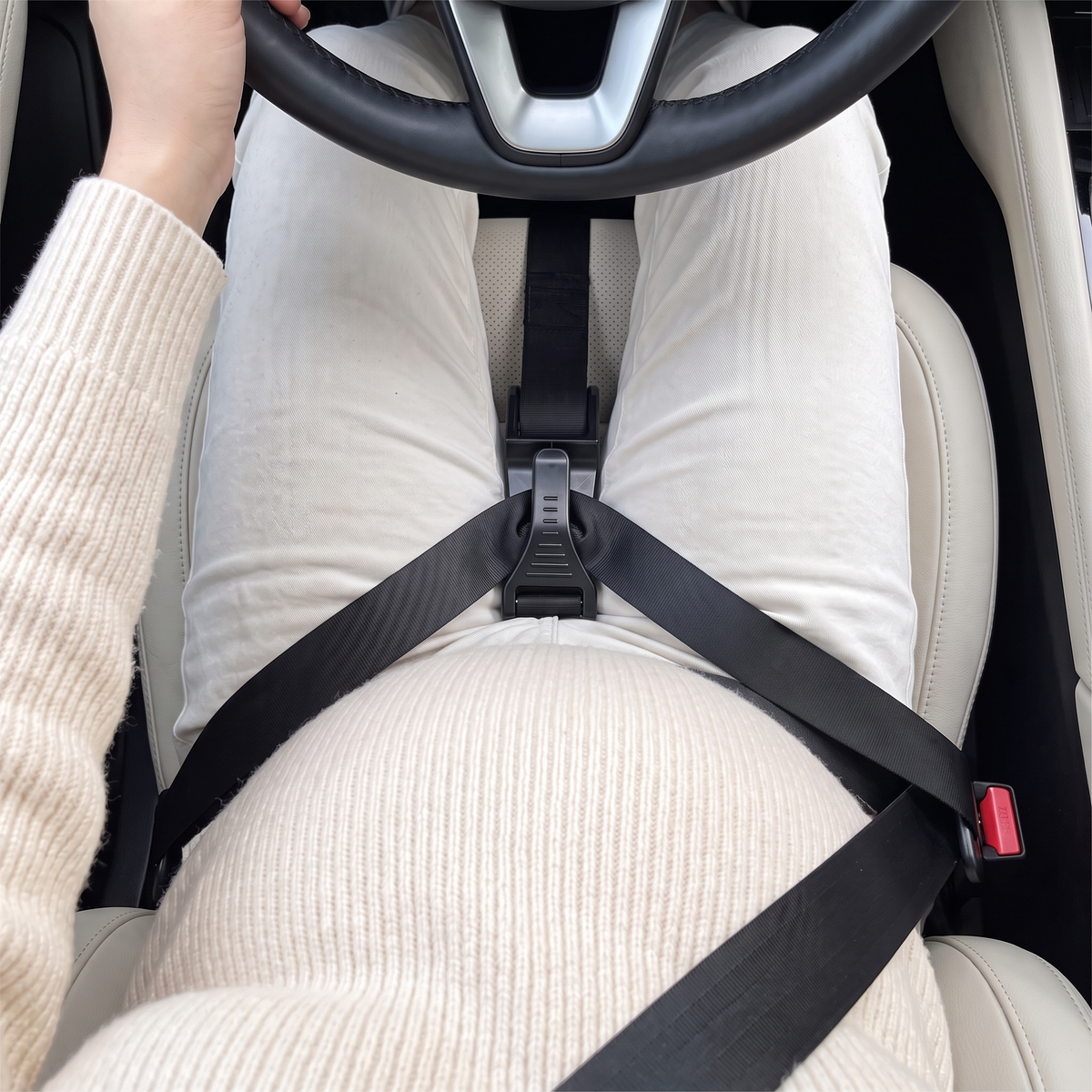 Driver's view of the seat belt adjuster holding the lap belt on the thighs, below the bump